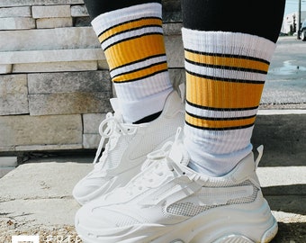 May include: White sneakers with a chunky sole and yellow and black striped socks.