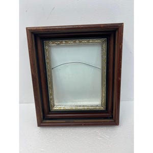 May include: A rectangular wooden picture frame with a dark brown finish and a distressed texture. The inner border features a decorative gold and black pattern. A thin metal hanging wire is attached across the center of the empty frame.