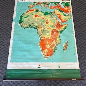 May include: A vintage map of Africa with a green, yellow, and orange color scheme. The map is rolled up and has a wooden dowel at the top. The map is labeled "Africa" and "RoadMark III".