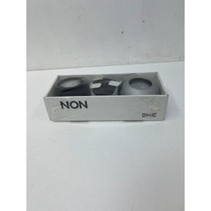 May include: A set of three small, round candle holders in a white box. One is black, one is white with a geometric design, and one is silver. The box has the word "NON" printed on it.