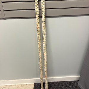 May include: Two white and black measuring sticks with red and black markings. The sticks are marked with numbers from 1 to 11, with each unit representing one foot. The sticks are used for measuring depth or height.