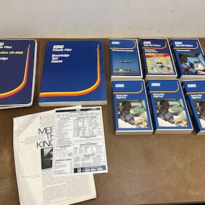 May include: A collection of aviation training materials, including books, CD-ROMs, and study guides. The items are primarily blue with yellow, orange, and red accents. The text on the items reads "KING Private Pilot" and "Knowledge Test Course."