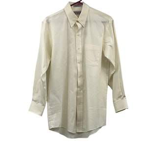 May include: A long-sleeved, button-down shirt in a light cream color. The shirt has a button-down collar, a chest pocket, and buttoned cuffs. The shirt is hanging on a hanger.