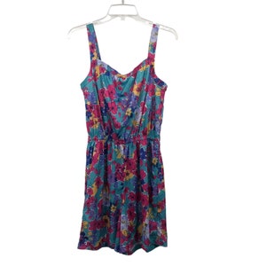 May include: A sleeveless floral jumpsuit with a turquoise background and pink, yellow, and purple flowers. The jumpsuit has a fitted bodice and a loose-fitting skirt.