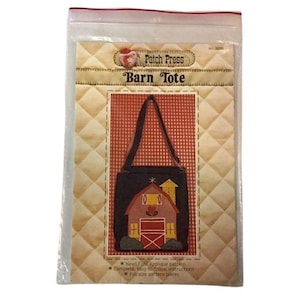 May include: A clear plastic package containing a "Barn Tote" applique pattern. The pattern features a black tote bag design with a red barn and yellow accents. The package includes instructions and full-size pattern pieces.