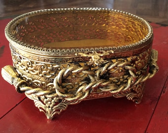 Oval Vanity Jewelry Box with Gilt Metal Rope & Tassel, Floral Pierced Filigree, Bevelled Amber Glass Lid and Gold Padded Interior circa 1965