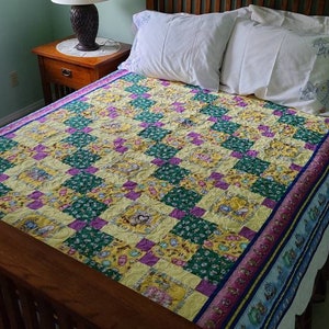 May include: A bed with a yellow, green, and purple patchwork quilt. The bed has a wooden headboard and footboard. There are two white pillows on the bed.