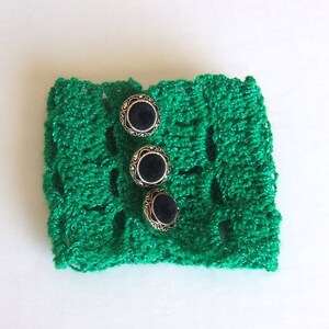 May include: Green crocheted bracelet with three black and gold buttons.