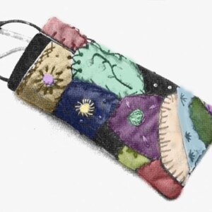 May include: A colourful patchwork glasses case with a black top and various fabric patches. The patches feature shades of blue, purple, green, and tan, with embroidered floral and sunburst designs. A pair of glasses is inside the case.