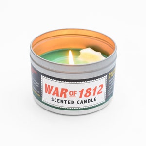 A lit War of 1812 candle with a half-melted wax White House on its surface.