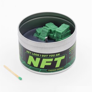 May include: A silver tin candle with a black wax base and green wax stacks shaped like money. The label reads "Hey look I got you an NFT - Themed Candle".