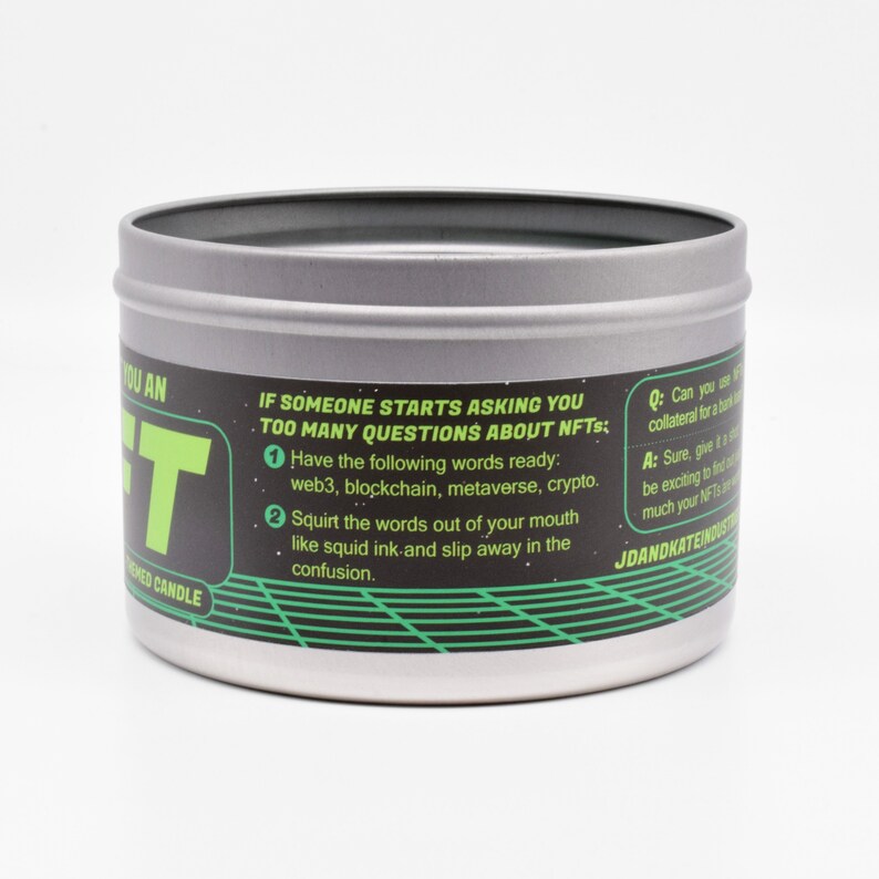 May include: A silver tin candle with a black and green label that reads "You an NFT" and includes instructions on how to respond to questions about NFTs. The label also includes the text "JDandKateIndustries".