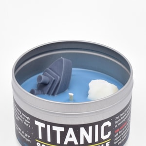 A close up of the surface of the Titanic Scented Candle, which features a tiny wax ice berg and a tiny wax sinking ship.