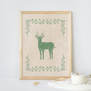 May include: A framed print with a green deer illustration surrounded by a green leafy border on a beige background.
