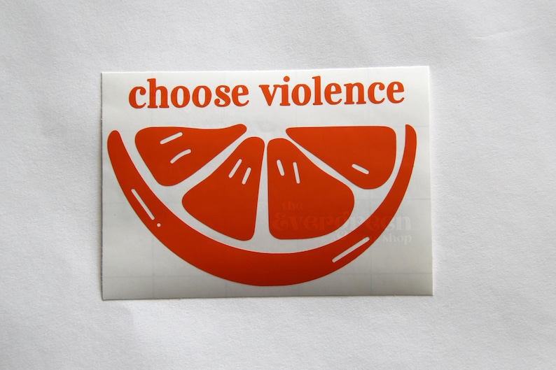 Puede incluir: Pegatina naranja con el texto "choose violence" y un gr&aacute;fico estilizado de rodaja de naranja.