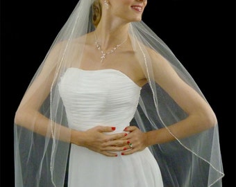 May include: A white bridal veil with a single row of sparkling crystals around the edge. The veil is made of soft tulle and is designed to be worn over a wedding dress.