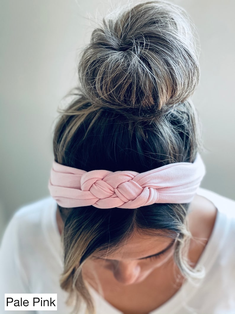 Op de afbeelding: Een lichtroze geknoopt hoofdband voor vrouwenhaar. Het hoofdband is gemaakt van een zachte, rekbare stof en is ontworpen om comfortabel te dragen.