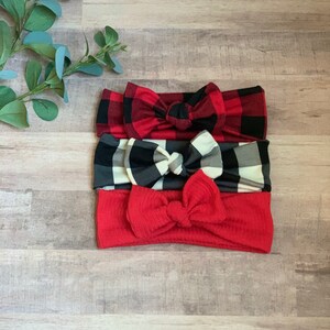May include: Set of three knotted headbands in red and black plaid, black and white plaid, and solid red.