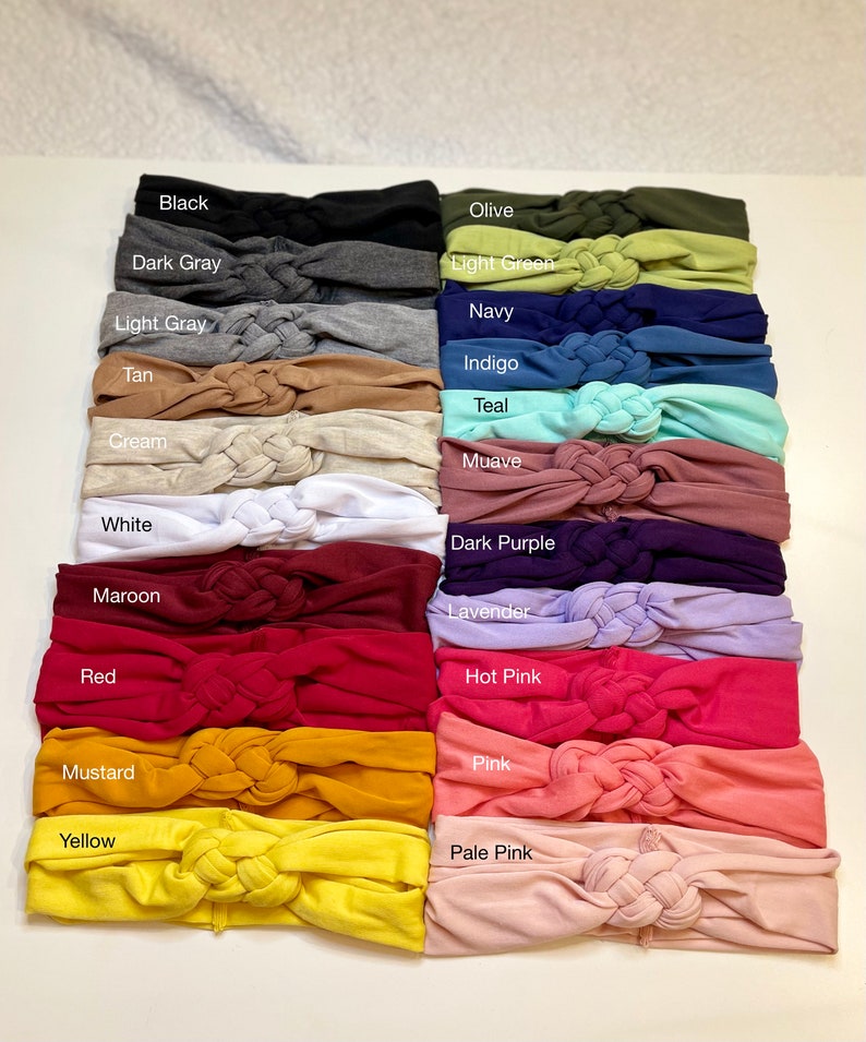 Op de afbeelding: Een set van 18 geknoopte haarbanden in verschillende kleuren, waaronder zwart, donkergrijs, lichtgrijs, bruin, cr&egrave;me, wit, donkerrood, rood, mosterd, geel, olijf, lichtgroen, marineblauw, indigo, turquoise, mauve, donkerpaars, lavendel, roze, roze en lichtroze.