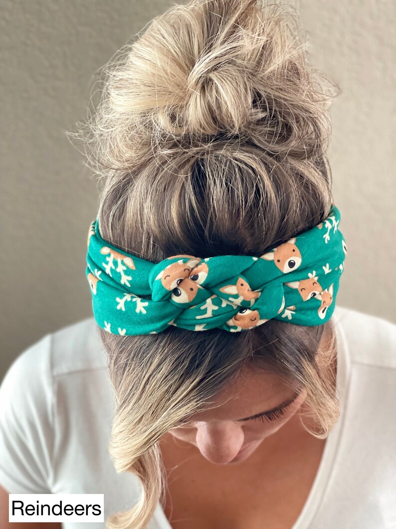 May include: A green headband with a white snowflake and reindeer pattern. The headband is knotted on top of the head.
