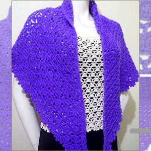 May include: A vibrant purple crochet shawl with a triangular shape. The shawl is draped over a white top, showcasing its openwork design. The intricate stitch pattern and rich color make it a stylish accessory.