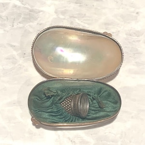 May include: A silver thimble with a green velvet lining inside a mother of pearl case.