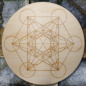 May include: A wooden circle with a geometric design etched into the surface. The design is a complex pattern of lines and circles, creating a visually appealing and intricate pattern.