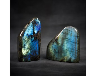 May include: Two polished labradorite stones with iridescent blue, green, and black colors. The stones are freeform and have a smooth, polished surface.