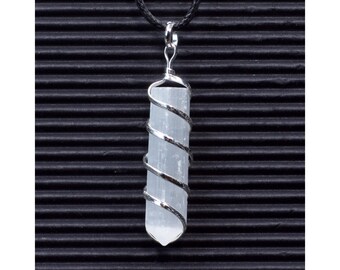 May include: A white selenite crystal wrapped in a silver wire spiral, hanging from a black cord. The crystal is a long, thin, rectangular shape with a pointed end.