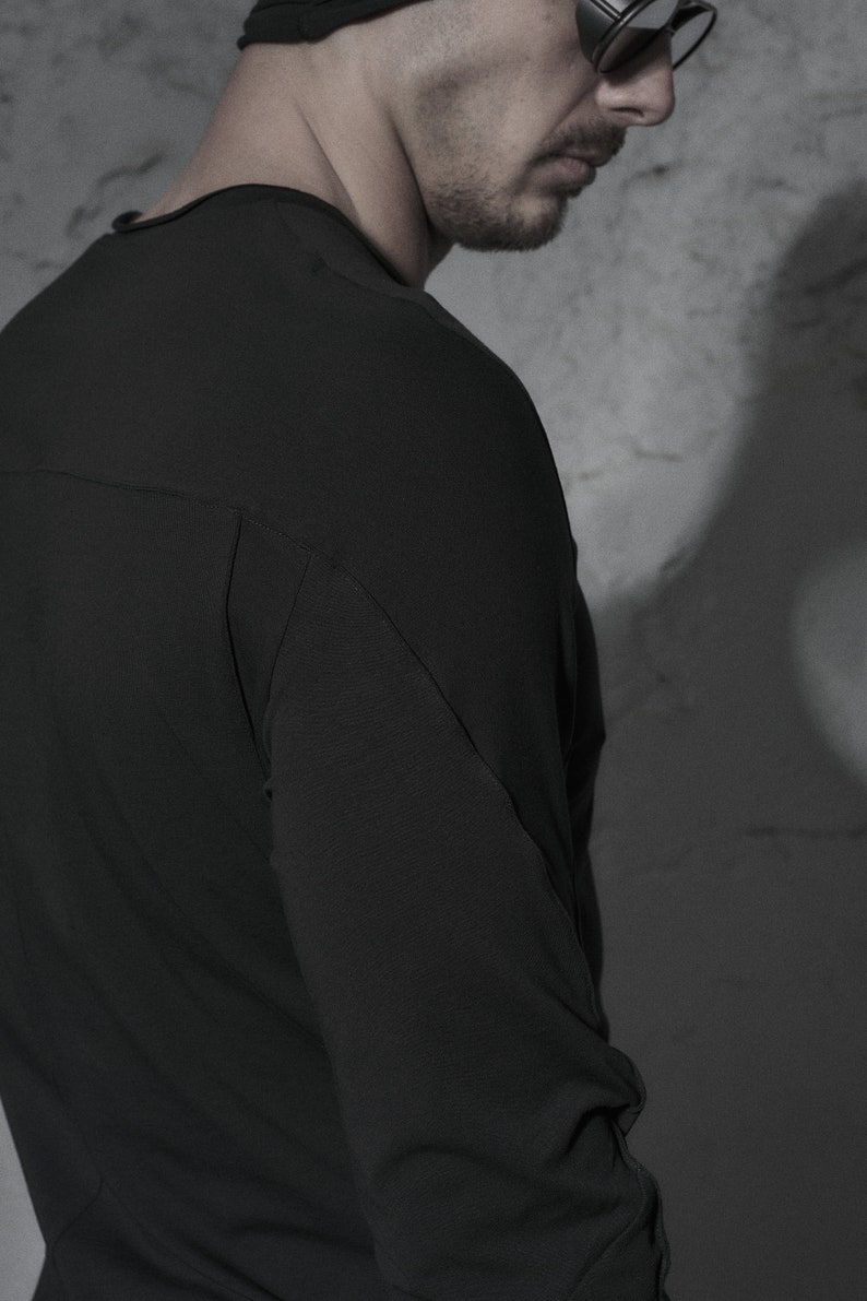 May include: A black long-sleeved shirt with a slightly fitted silhouette. The shirt has a simple design and a smooth texture.