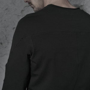 May include: A black long-sleeved shirt with a crew neck and a seam down the back.