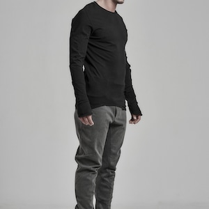 May include: A man wearing a black long-sleeved shirt, gray pants, and black beanie with sunglasses.