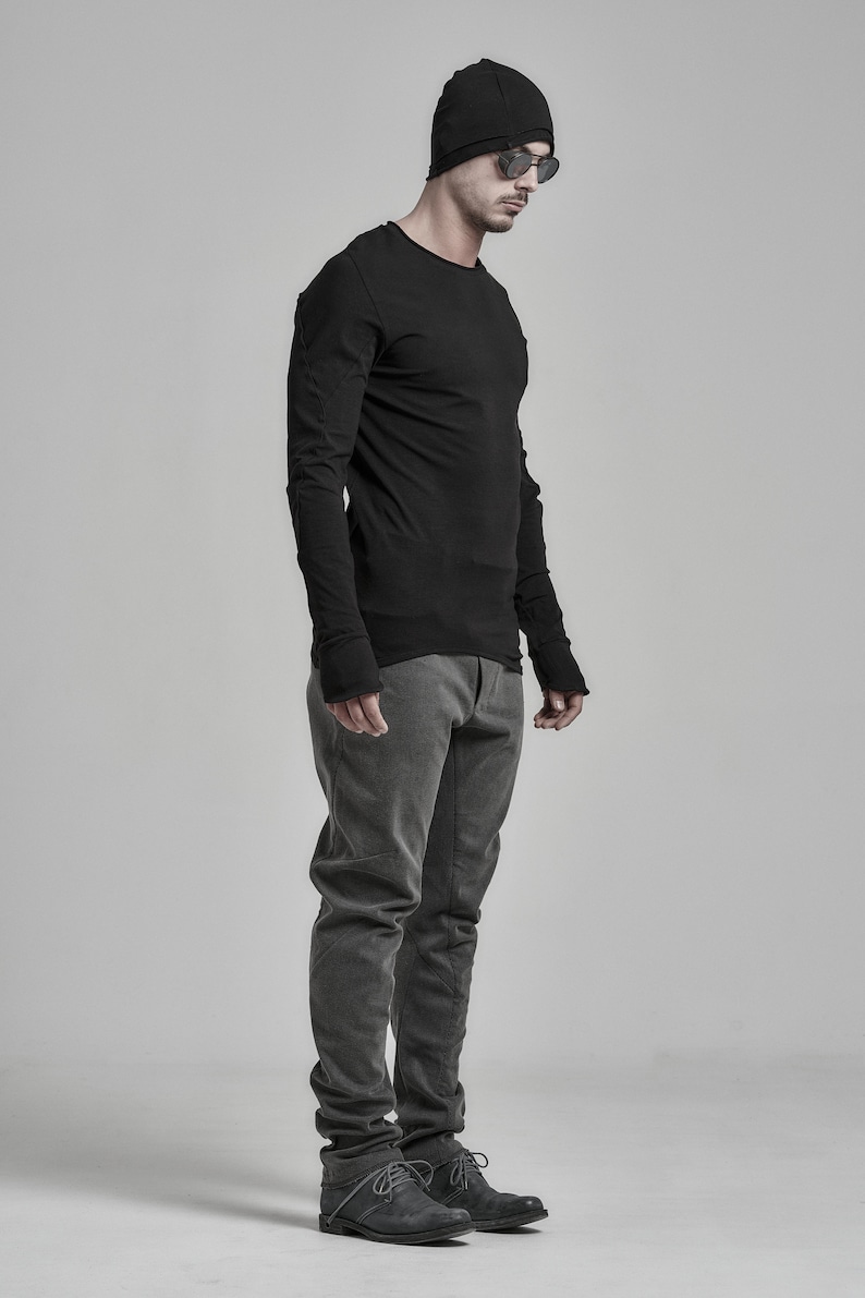 May include: A man wearing a black long-sleeved shirt, gray pants, and black beanie with sunglasses.