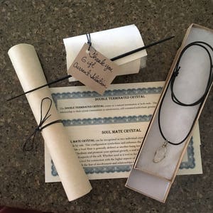 May include: A double terminated crystal necklace on a black cord in a small box. The box has a certificate that reads "Double Terminated Crystal" and "Soul Mate Crystal". The certificate explains that the double terminated crystal is a natural termination at both ends. The Soul Mate Crystal is recognized as two individual crystals side by side. This configuration symbolizes and enhances the idea of a Soul Mate, generally defined as another being loving and promoting spiritual growth.