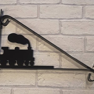 May include: Black metal wall-mounted sign holder shaped like a train engine. The holder is designed to hang a sign or plaque.