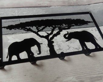 May include: Black metal key holder featuring a silhouette of two elephants and a tree. The key holder has four hooks.