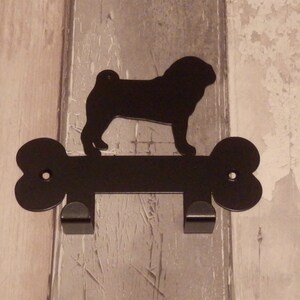 May include: Black metal dog bone shaped hook with a silhouette of a pug dog on top.