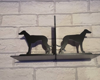 May include: Black metal bookends shaped like greyhounds. The bookends are on a white brick wall.