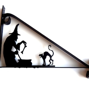 May include: Black metal wall mount with a silhouette of a witch stirring a cauldron and a black cat. The mount is shaped like a triangle with a decorative scroll at the end.