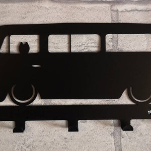 May include: Black metal key holder shaped like a vintage van with four hooks. The van has a silhouette of a person in the window.