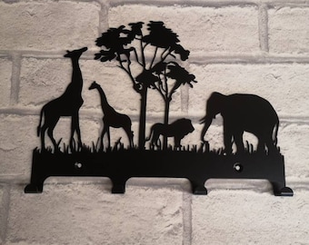 May include: Black metal key holder featuring a silhouette of a giraffe, elephant, lion, and a tree. The key holder has three hooks.