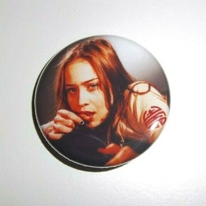 Peut inclure: Un bouton rond avec une image s&eacute;pia d'une femme aux cheveux roux. Elle regarde le spectateur avec une expression s&eacute;rieuse. Le bouton a une finition brillante et un bord noir.