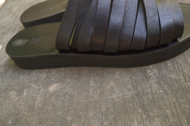 Puede incluir: Sandalias de cuero negro con m&uacute;ltiples tiras a trav&eacute;s del pie y una suela de plataforma gruesa.