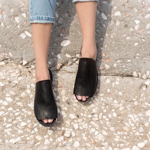 May include: A pair of black leather open-toe sandals with a textured surface.