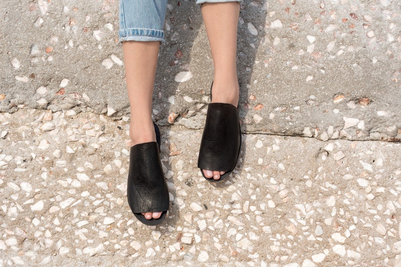 May include: A pair of black leather open-toe sandals with a textured surface.