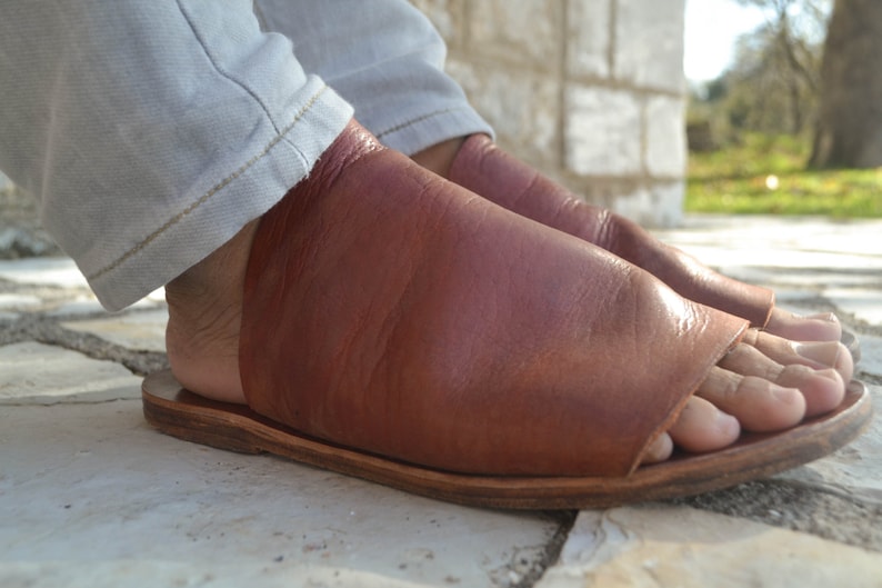 Puede incluir: Un par de sandalias de cuero marr&oacute;n con un dise&ntilde;o de dedo abierto. Las sandalias tienen un estilo simple y minimalista y est&aacute;n hechas de cuero de alta calidad.