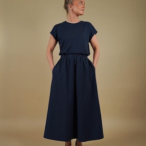 May include: A dark navy blue two-piece set consisting of a short-sleeved crew neck top and a high-waisted, ankle-length skirt with an elasticized waistband and side pockets. The ensemble features a solid color and a simple, clean silhouette.