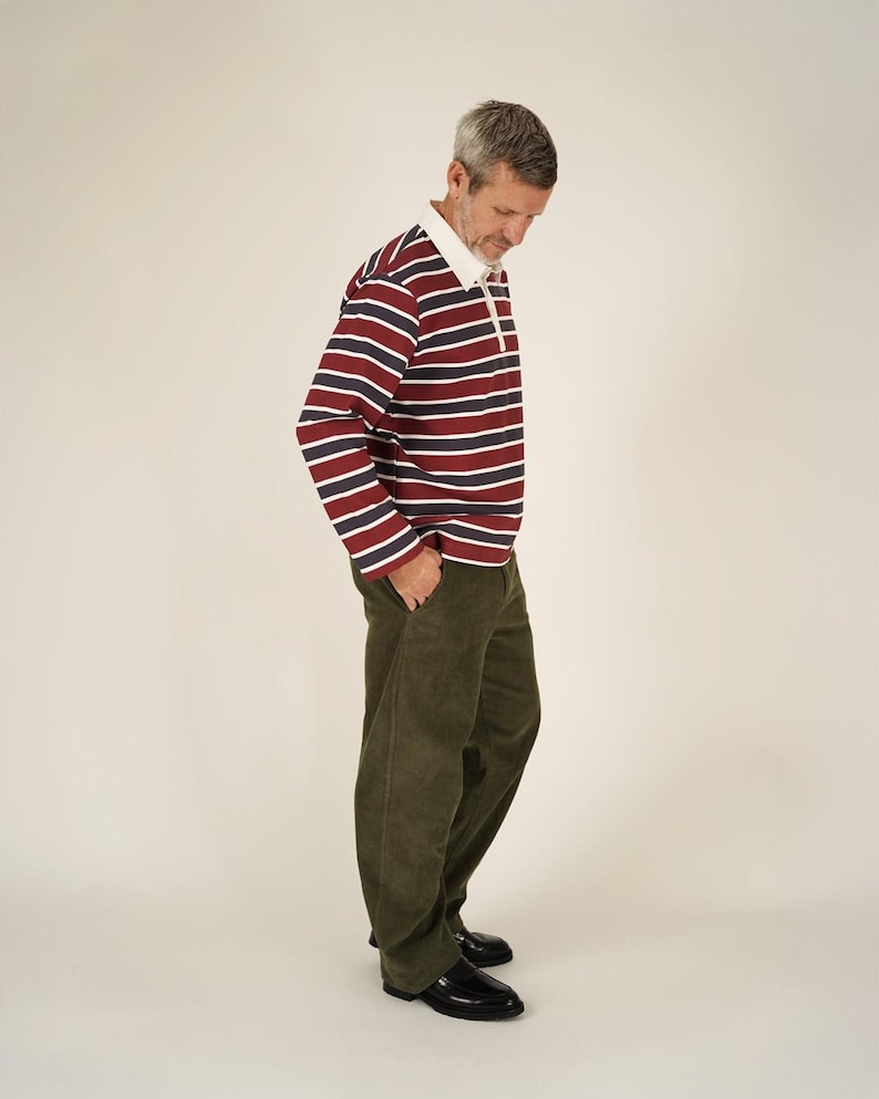 May include: A person wearing a rugby shirt with horizontal stripes in burgundy, navy, and white, paired with olive green corduroy pants and black leather shoes. The shirt has a white collar.