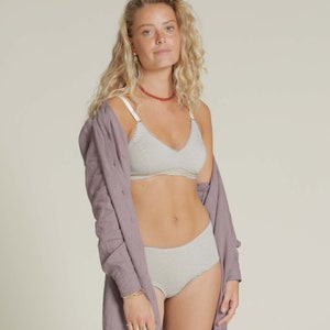 Puede incluir: Conjunto de sujetador y ropa interior a rayas claras. El sujetador tiene tirantes finos y un dise&ntilde;o de cuello en V. La ropa interior es de talle alto. Una camisa larga de color p&uacute;rpura claro est&aacute; drapeada sobre los hombros.