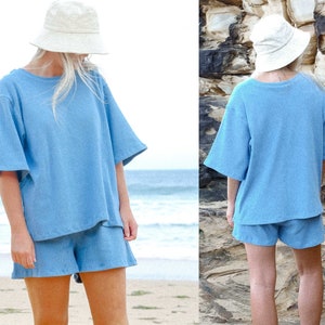 May include: A light blue cotton short set with a relaxed fit. The top has a round neckline and short sleeves. The shorts have a high waist and a relaxed fit.